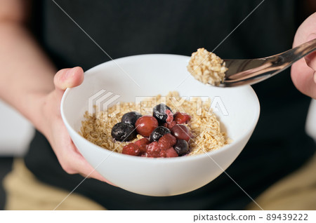 Young vegan woman eating oatmeal 89439222