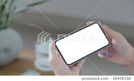 Close up view woman holding smart phone in horizontal position. Empty screen for advertising text. 89440190