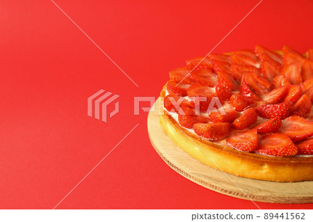Round board with strawberry tart on red background Round board with strawberry tart on red background 89441562