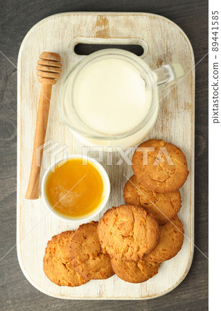Milk, honey and pumpkin cookies on gray wooden table 89441585