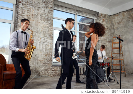 Repetition of multi ethnic jazz band in loft. Bass guitar player, electric guitar player, saxophonist and drummer at loft. Jazz music and jam session concept. passion for music and youth culture Repetition of multi ethnic jazz band in loft. Bass guitar player, electric guitar player, saxophonist and drummer at loft. Jazz music and jam session concept. passion for music and youth culture 89441919