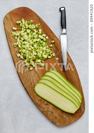 Zucchini cut into cubes and layers on a wooden cutting board on a concrete light table 89441920