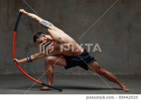 A ninja man holds on to a fighting stick and attacks close-up on gray studio background 89442010