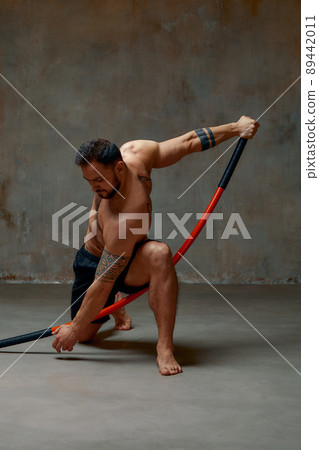 An experienced fighter, stands in a fighting posture with a fighting bamboo stick. Sport banner 89442011