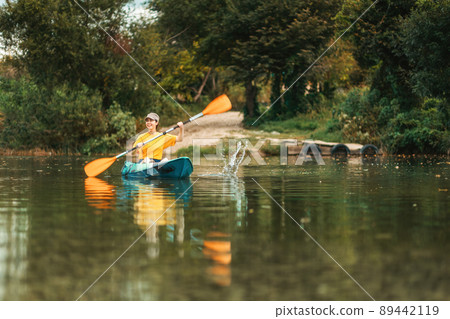 Kayaking. Happy young pretty woman floating in blue kayak at river. Copy space. Low angle view from the water. The concept of World Tourism Day 89442119
