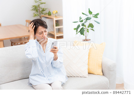 坐在沙發上的中年婦女（智能手機、電子郵件、互聯網） 89442771