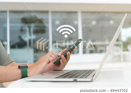 In a cafe shop background, a woman uses a laptop with a wifi icon. Social networking concept. 89443502