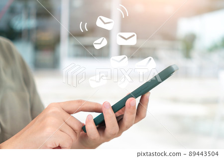 A woman's hand sends and receives emails on her smartphone. Concept of business communication technology. 89443504