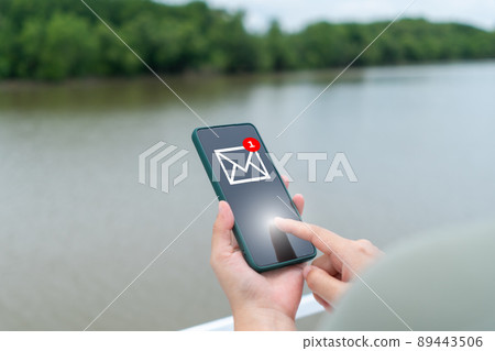 A woman's hand sends and receives emails on her smartphone. Concept of business communication technology. A woman's hand sends and receives emails on her smartphone. Concept of business communication technology. 89443506