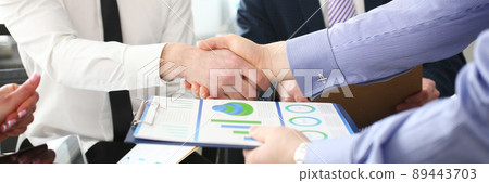 Close-up of smart colleagues smiling and shaking hand with prudent boss. Close-up of smart colleagues smiling and shaking hand with prudent boss. 89443703