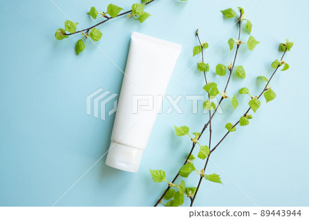 White Cream tube and birch branches with young small leaves on blue background. Cosmetic skincare product blank plastic package. White bottle of unbranded lotion, balsam, toothpaste mockup, flat lay. White Cream tube and birch branches with young small leaves on blue background. Cosmetic skincare product blank plastic package. White bottle of unbranded lotion, balsam, toothpaste mockup, flat lay. 89443944