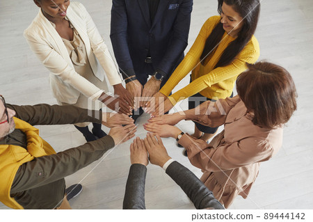 Team of happy multiracial business people standing in a circle and putting their hands together 89444142