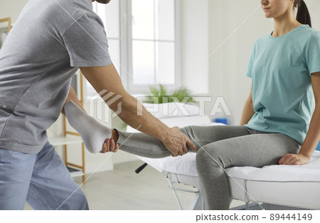 Female patient receiving professional medical care in rehabilitation center after leg injury. 89444149