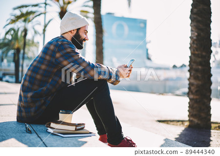 Middle Eastern student chatting with followers from social network via app on mobile phone Middle Eastern student chatting with followers from social network via app on mobile phone 89444340