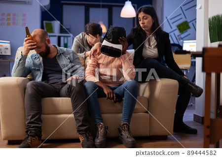 Disappointed woman with vr headset losing at video games on tv console, using virtual reality glasses and controller to play for entertainment. Office colleagues meeting for drinks after hours. 89444582
