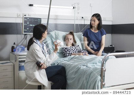 Clinic pediatric specialist recommending ill patient girl right medicine for illness remission. Hospital pediatrist specialist talking with attentive mother about illness treatment. Clinic pediatric specialist recommending ill patient girl right medicine for illness remission. Hospital pediatrist specialist talking with attentive mother about illness treatment. 89444723