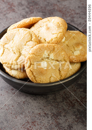 Fresh made Macadamia Cookies with white chocolate closeup in the black bowl close-up. Vertical Fresh made Macadamia Cookies with white chocolate closeup in the black bowl close-up. Vertical 89444896