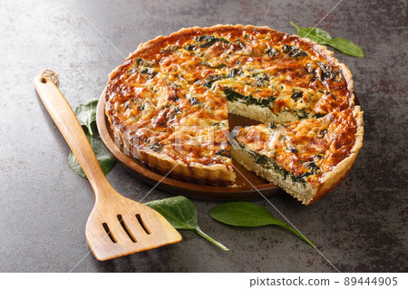 Savory tart of rich egg custard, spinach and cheese with cut out a slice on the plate close-up. Hotizontal Savory tart of rich egg custard, spinach and cheese with cut out a slice on the plate close-up. Hotizontal 89444905