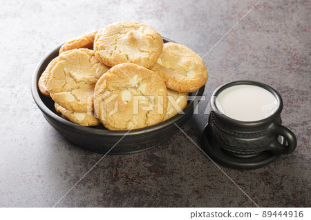 White Chocolate Caramel soft and macadamia nuts baked cookies served with cup of milk close-up. Horizontal White Chocolate Caramel soft and macadamia nuts baked cookies served with cup of milk close-up. Horizontal 89444916