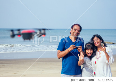 happy indian family are operating the drone by remote control in the beach in Goa happy indian family are operating the drone by remote control in the beach in Goa 89445689
