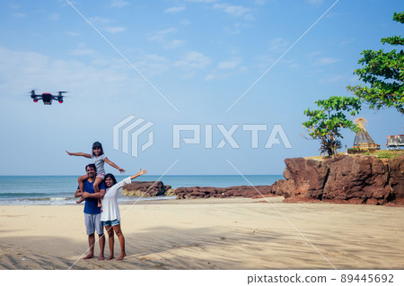 happy indian family are operating the drone by remote control in the beach in Goa happy indian family are operating the drone by remote control in the beach in Goa 89445692