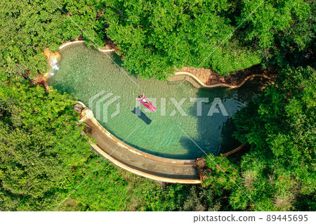 girl floating in the pool water relaxing on pink inflatable mattress in blue swimmingpool remote work and freelance top view green tree luxury eco hotel in Goa India girl floating in the pool water relaxing on pink inflatable mattress in blue swimmingpool remote work and freelance top view green tree luxury eco hotel in Goa India 89445695