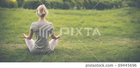 Woman sitting in active wear in lotus position in nature. Woman sitting in active wear in lotus position in nature. 89445696