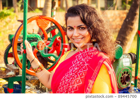 beautuful induan woman in red sari standing near sugarcane juice maker apparatus machine , plantation summer farm background. small business start up beautuful induan woman in red sari standing near sugarcane juice maker apparatus machine , plantation summer farm background. small business start up 89445700