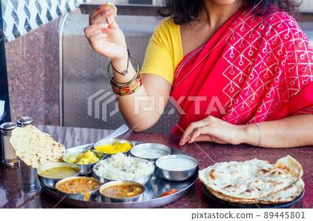 close up photo of Indian traditional vegetarian thali from rice, dal, potatoes, tomato salad on metal plate ,female hands roti india tortilla Chapati close up photo of Indian traditional vegetarian thali from rice, dal, potatoes, tomato salad on metal plate ,female hands roti india tortilla Chapati 89445801