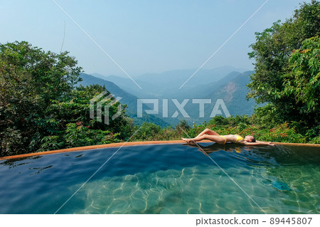 woman enjoying a sun in the infinity pool in eco plastic free zone ,mountain and hills background woman enjoying a sun in the infinity pool in eco plastic free zone ,mountain and hills background 89445807
