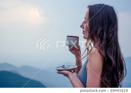 girl drinking cup of hot tea on top mountain in india herb plantation 89445829