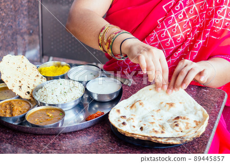 close up photo of Indian traditional vegetarian thali from rice, dal, potatoes, tomato salad on metal plate ,female hands roti india tortilla Chapati close up photo of Indian traditional vegetarian thali from rice, dal, potatoes, tomato salad on metal plate ,female hands roti india tortilla Chapati 89445857