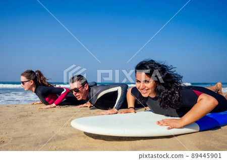 surf instructor and two girls beginner surfers try to stand up on surfboard on lesson in Goa India 89445901