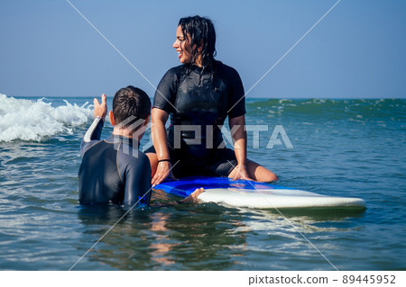 man instructor next surfboard with indian woman waitinh a big wave in surf class in Goa sea 89445952