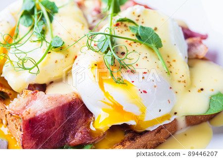 Eggs benedict on crispy toast with bacon and traditional hollandaise sauce. Delicious breakfast concept. Eggs benedict on crispy toast with bacon and traditional hollandaise sauce. Delicious breakfast concept. 89446207