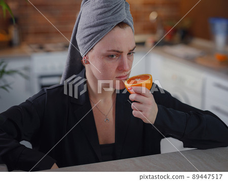 Sick woman trying to sense smell of fresh orange Sick woman trying to sense smell of fresh orange 89447517