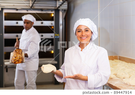 Woman baker demonstrates ready dough for baking in oven 89447914