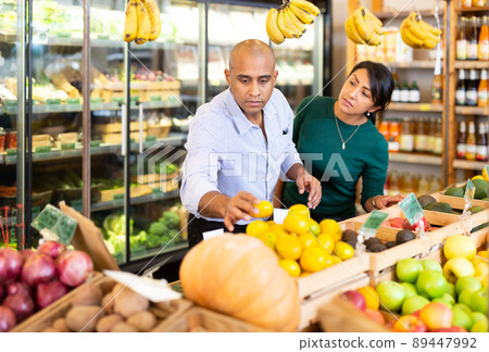 Hispanic man with wife choosing mandarines in grocery store 89447992