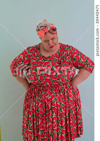 Plus size sexy model woman with trendy makeup, fashionable blonde in colorful dress posing at the cyan or light blue background in studio. 89448475