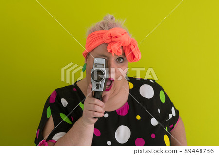 plus size smiling woman with funny emotional face expression with vintage camera in dress isolated on green background, traveler on vacation, summer fashion style, excited tourist. 89448736