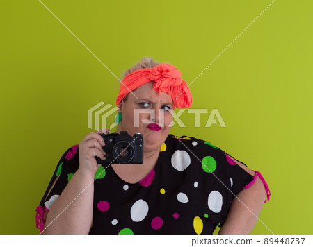plus size smiling woman with funny emotional face expression with vintage camera in dress isolated on green background, traveler on vacation, summer fashion style, excited tourist. plus size smiling woman with funny emotional face expression with vintage camera in dress isolated on green background, traveler on vacation, summer fashion style, excited tourist. 89448737