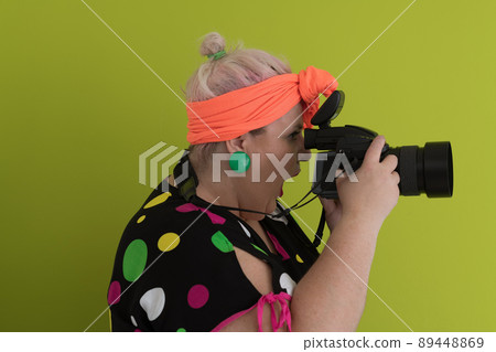 plus size smiling woman with funny emotional face expression with vintage camera in dress isolated on green background, traveler on vacation, summer fashion style, excited tourist. 89448869