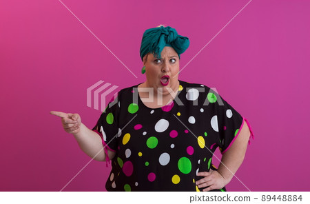 Plus size sexy model woman with trendy makeup, fashionable blonde in black short dress posing at the pink background in studio. 89448884
