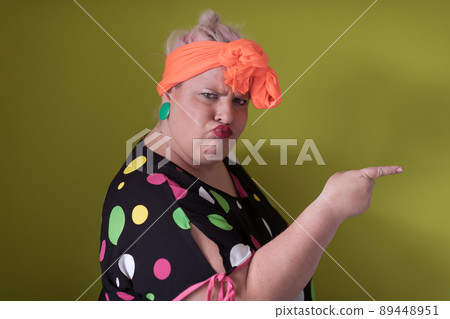 Plus size sexy model woman with trendy makeup, fashionable blonde in black short dress posing at the green background in studio. 89448951