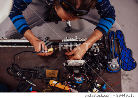 Industrial worker man soldering cables of manufacturing equipment in a factory. Selective focus 89449113