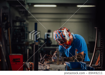 Professional Heavy Industry Welder Working Inside factory, Wears Helmet and Starts Welding. Selective Focus Professional Heavy Industry Welder Working Inside factory, Wears Helmet and Starts Welding. Selective Focus 89449211
