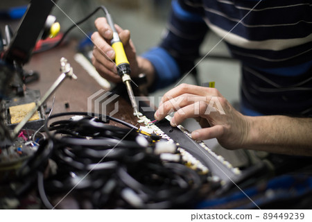 Industrial worker man soldering cables of manufacturing equipment in a factory. Selective focus 89449239