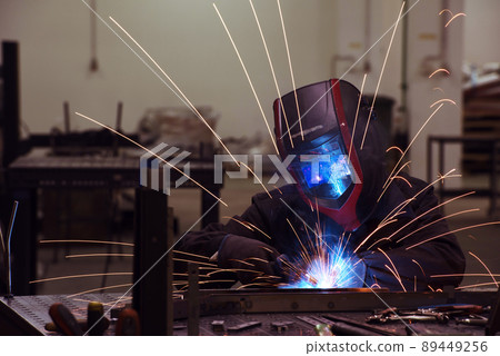 Professional Heavy Industry Welder Working Inside factory, Wears Helmet and Starts Welding. Selective Focus Professional Heavy Industry Welder Working Inside factory, Wears Helmet and Starts Welding. Selective Focus 89449256