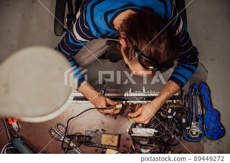 Industrial worker man soldering cables of manufacturing equipment in a factory. Selective focus Industrial worker man soldering cables of manufacturing equipment in a factory. Selective focus 89449272