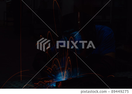 Professional Heavy Industry Welder Working Inside factory, Wears Helmet and Starts Welding. Selective Focus Professional Heavy Industry Welder Working Inside factory, Wears Helmet and Starts Welding. Selective Focus 89449275